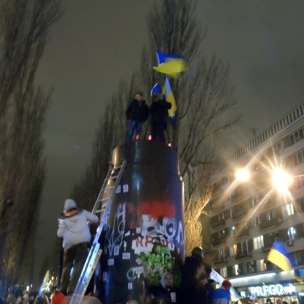 Demonstranti na prázdném podstavci stržené Leninovy sochy v Kyjevě 8. prosince 2013